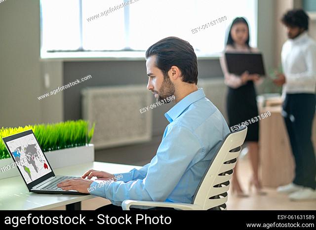 Working day. Dark-haired man working at the laptop in the office