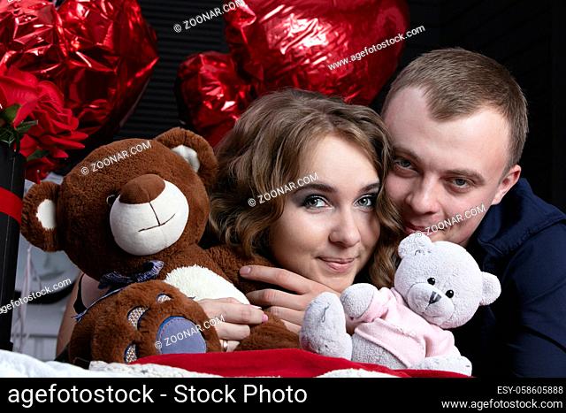 Boyfriend and girlfriend on Valentine's Day. Portrait of lovers. A man and a beautiful woman with flowers and bears