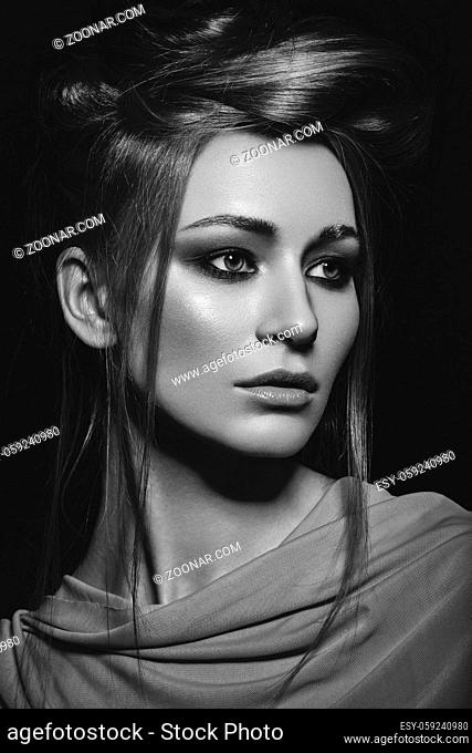 beautiful young woman with golden makeup and many chains on neck. beauty portrait on black background. monochrome