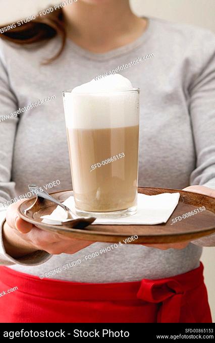 Woman serving caffe latte on tray