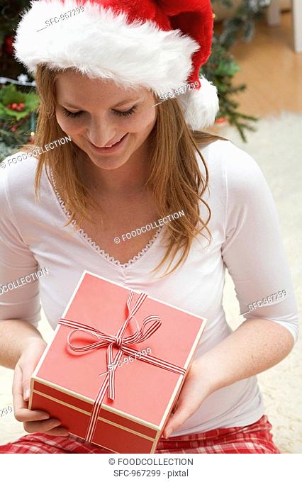 Woman in Father Christmas hat looking at Christmas gift