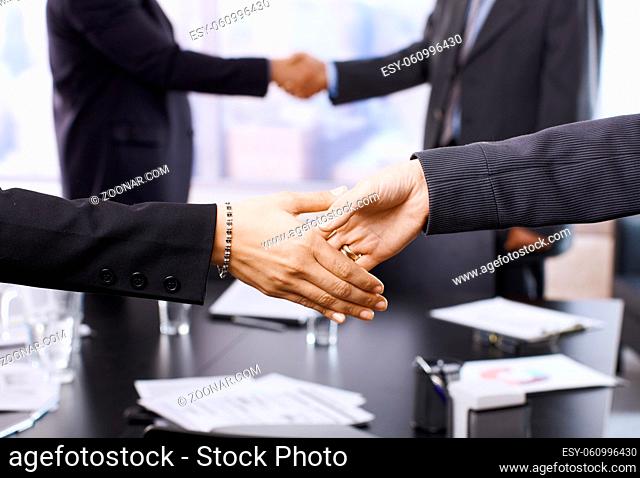 Businesspeople shaking hands in skyscraper office on meeting. Focus on hands