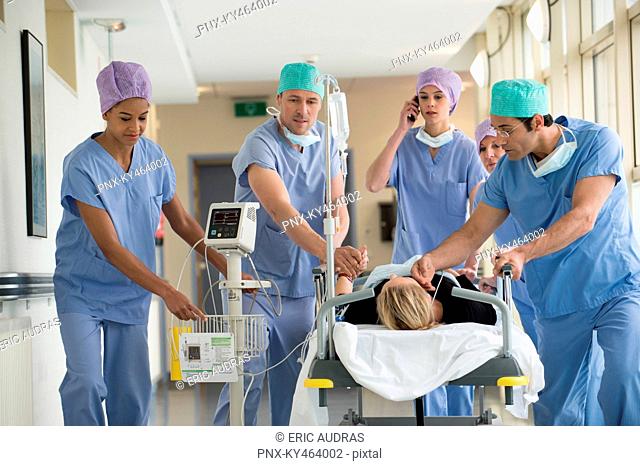 Medical professionals pushing patient on gurney in a hospital