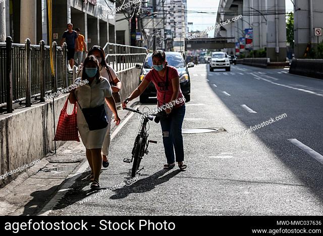 People walk along an almost empty street during a COVID-19 lockdown in Manila, Philippines