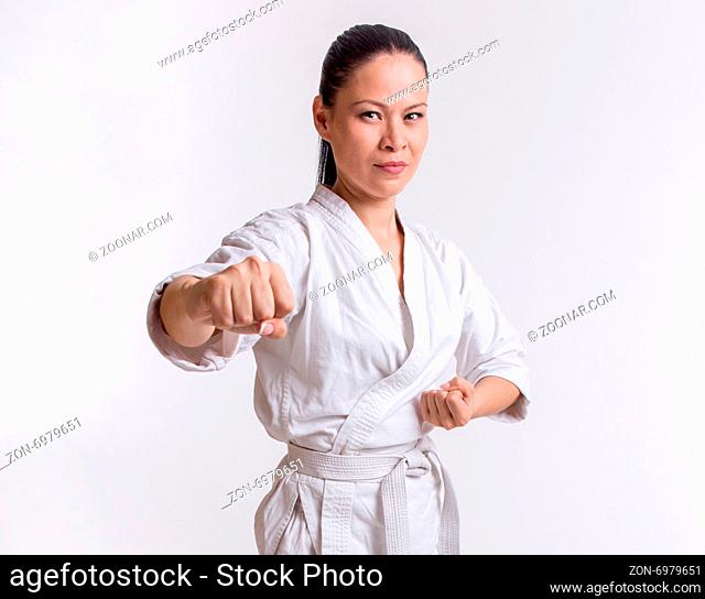 Funny woman in kimono show punch in martial art exercise on white