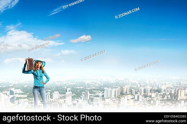 Beautiful woman traveler in hat with suitcase on modern city background