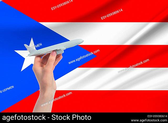 Airplane in hand with national flag of Puerto Rico. Travel to Puerto Rico