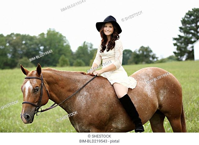 Woman riding horse in rural field