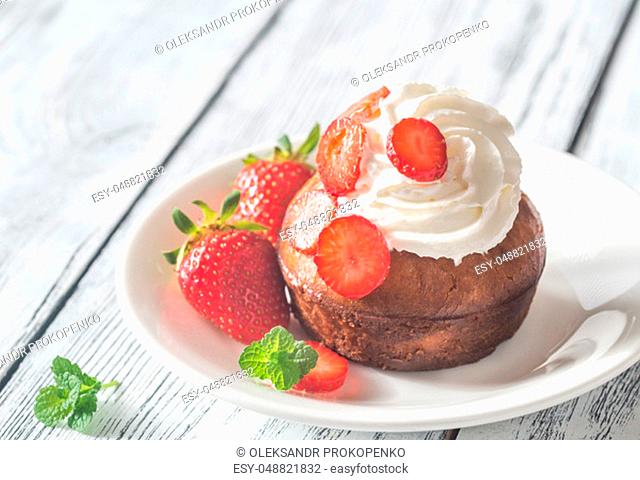 Rum baba decorated with whipped cream and fresh strawberries