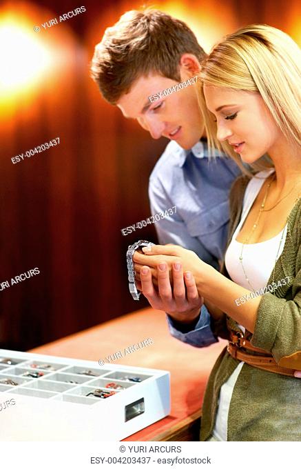Attractive young couple admiring a male wristwatch in a jewellery store