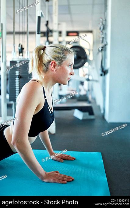 Junge Frau macht eine Yoga Übung oder dehnt den Körper auf der Yogamatte
