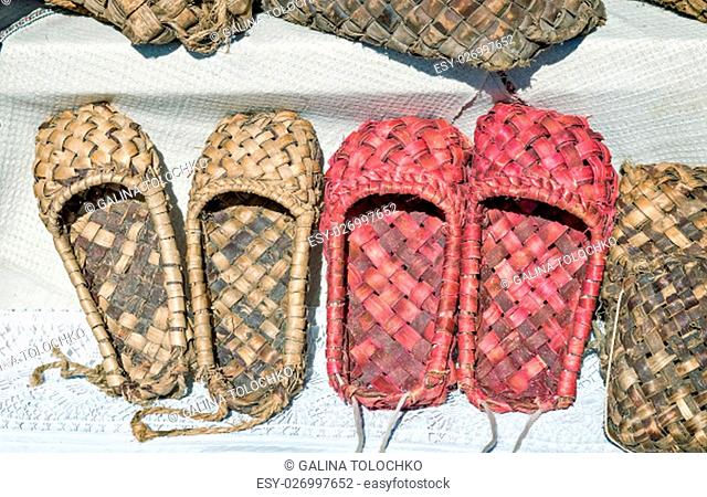 Demonstration of ancient objects of rural life: woven from tree bark sandals. Shoes of the peasants in ancient Russia