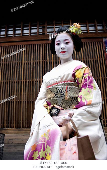Gion District, the neighbourhood where Geisha live and perform. Three-quarter portrait of smiling Maiko, or apprentice Geisha with hair pinned up with...