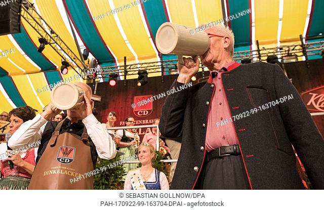 Stuttgart's mayor Fritz Kuhn (L, The Greens) and Winfried Kretschmann, Premier of Baden-Wuerttemberg, drink beer during the opening ceremony of the 172nd...