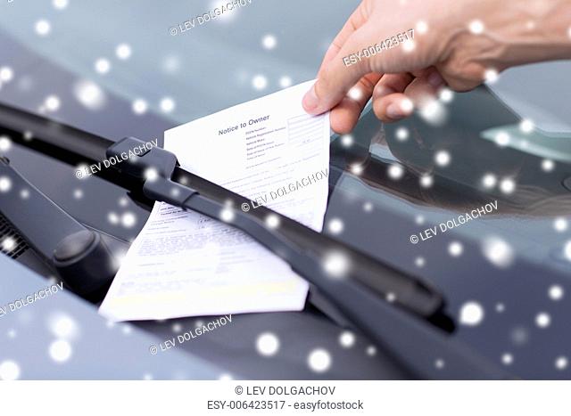transportation and vehicle concept - close up of male hand with parking ticket on car windscreen