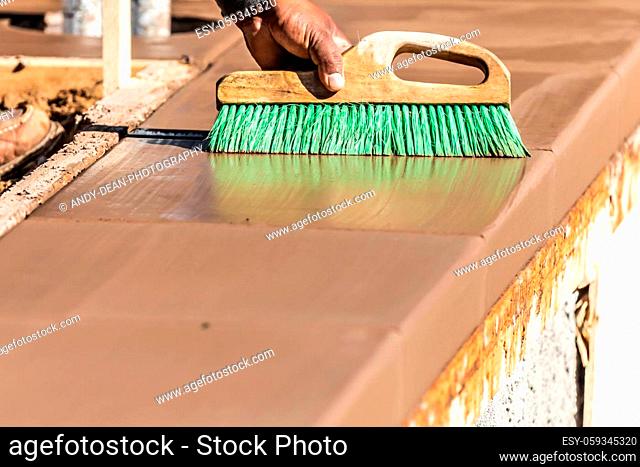 Construction Worker Using Brush On Wet Cement Forming Coping Around New Pool