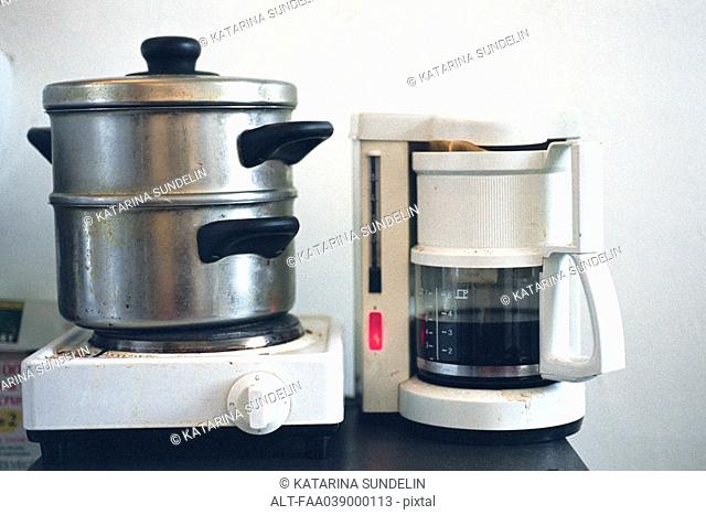 Steamer on hotplate set next to coffee maker on counter