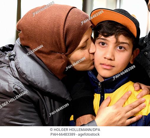 Afghan refugee boy Mahdi Rabani gets a kiss his mother Shockria in the arrivals hall of the Hanover-Langenhagen Airport with a bouquet of flowers in Hanover
