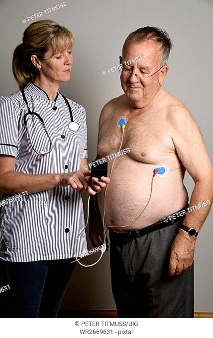 England Uk Member of a Hospial Cardiac Measurement Team Installing A Ambulatory Ecg Monitor To An Overweight Male Patient