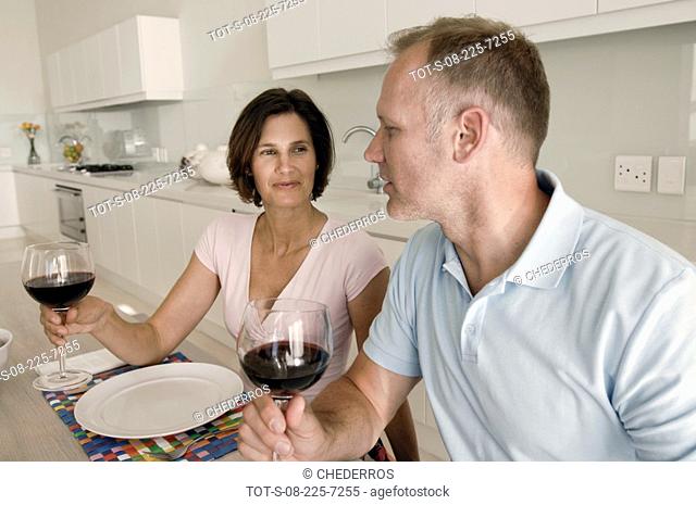Mid adult couple looking at each other and holding wine glasses