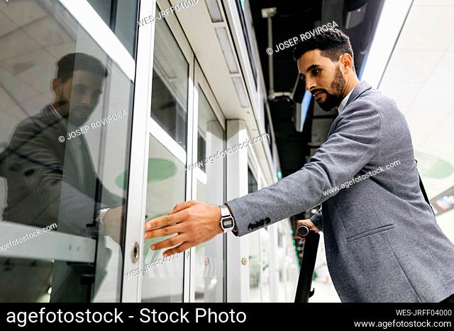 Young businessman pressing the opening button to get on an automatic subway train