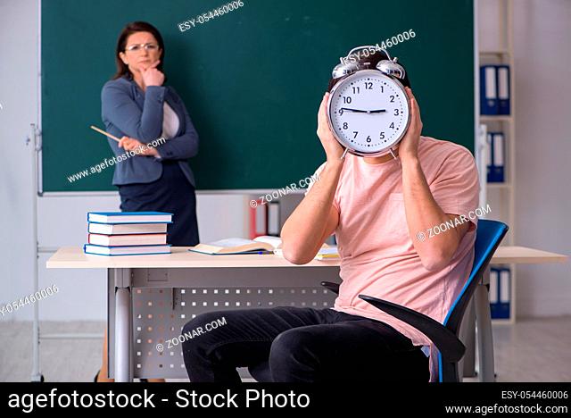 The old female teacher and male student in the classroom
