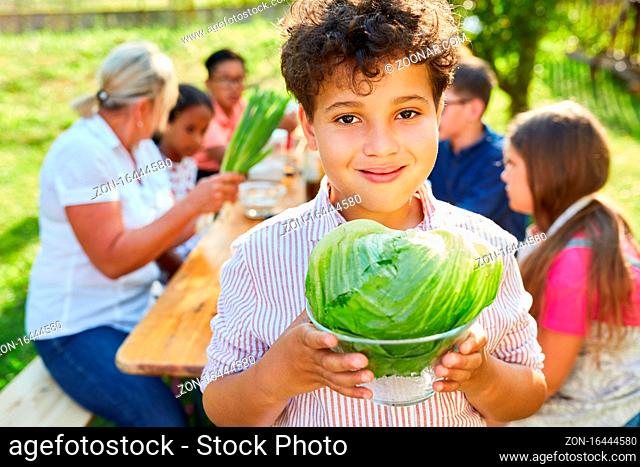 Kind mit Salatkopf im Kochkurs für gesunde vegetarische Ermährung im Ferienlager