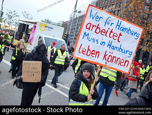 22 November 2023, Hamburg: A participant at a rally on Steintorwall holds a banner with the inscription ""Those who work for Hamburg must be able to live in...