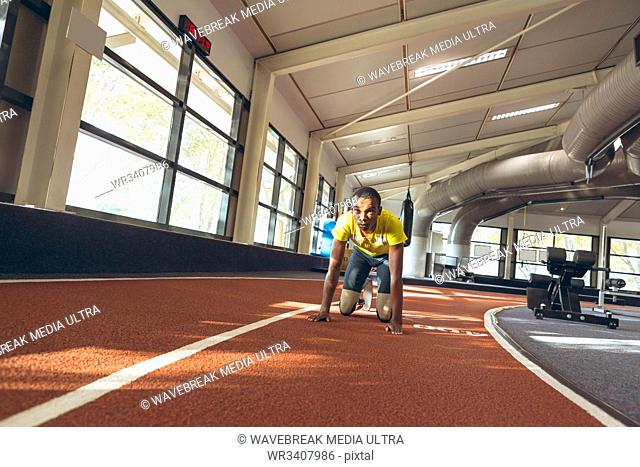 Front view of disabled African American male relaxing on a running track in fitness center