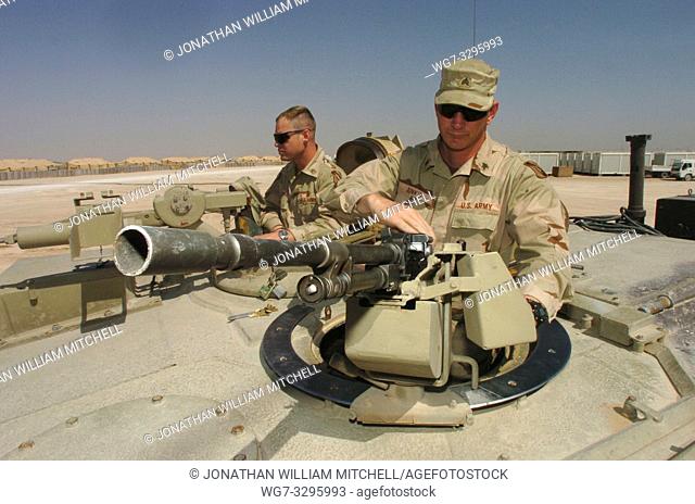 IRAQ FOB Hotel -- 30 Mar 2005 -- US Army Sgt Scott Junkin (right) mounts an M-240 machine gun on top of an M1A1 Abrams tank as he and Staff Sgt
