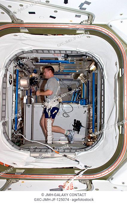 NASA astronaut Doug Wheelock, Expedition 25 commander, equipped with a bungee harness, exercises on the Combined Operational Load Bearing External Resistance...