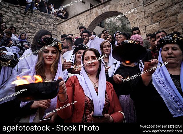 19 April 2022, Iraq, Dohuk: Iraqi Yazidi women hold lit candles and torches at the Lalish mountain valley and temple, the holiest shrine of the Yazidis