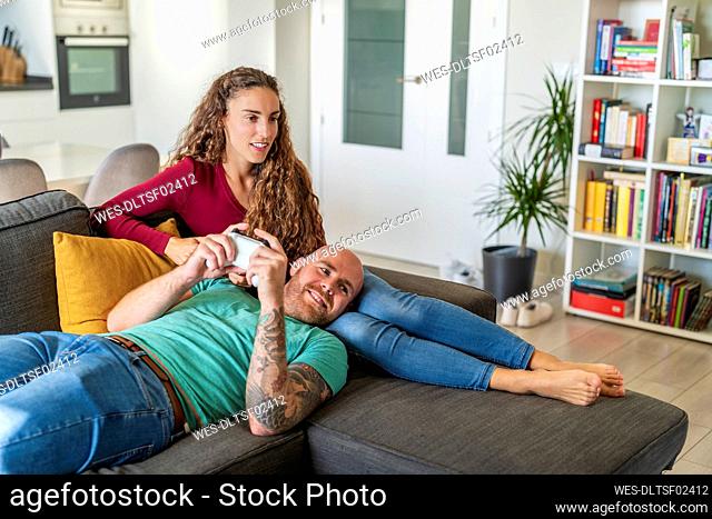 Man playing video game on woman lap at home