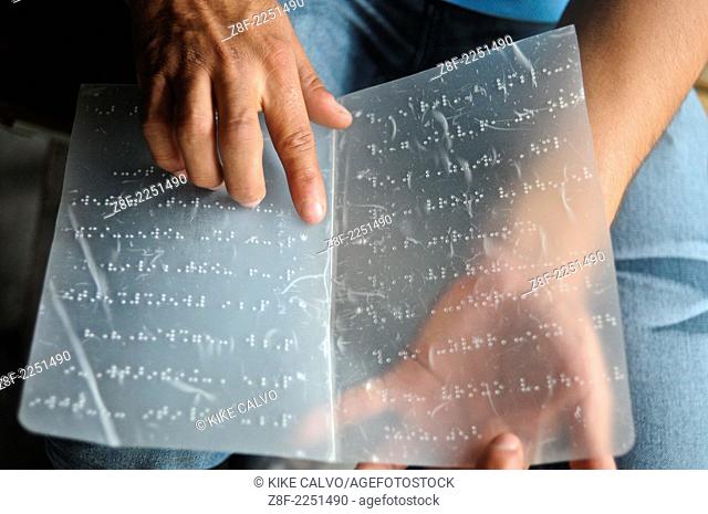 Blind man reading from a page written in braille