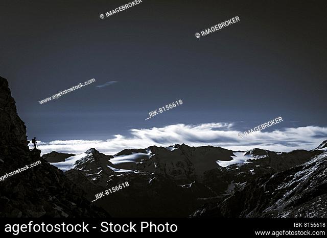 Climber on rocky outcrop with South Tyrolean mountains at blue hour, Martell Valley, Naturno, South Tyrol, Italy, Europe