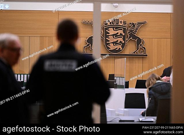 07 December 2023, Baden-Württemberg, Stuttgart: Security forces and lawyers stand in a courtroom at Stuttgart Regional Court at the start of a trial for fifteen...