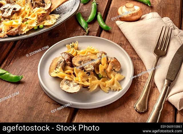 Mushroom and cheese pasta. Farfalle with cremini and green peas, easy Italian vegetarian recipe