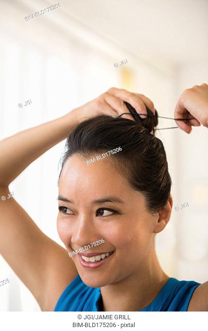 Chinese woman tying her hair in bun