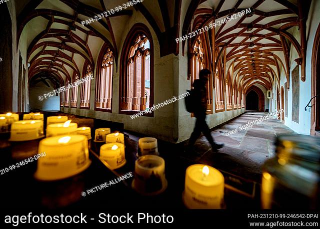 10 December 2023, Rhineland-Palatinate, Mainz: A visitor to St. Stephen's parish church walks past sacrificial candles in the cloister