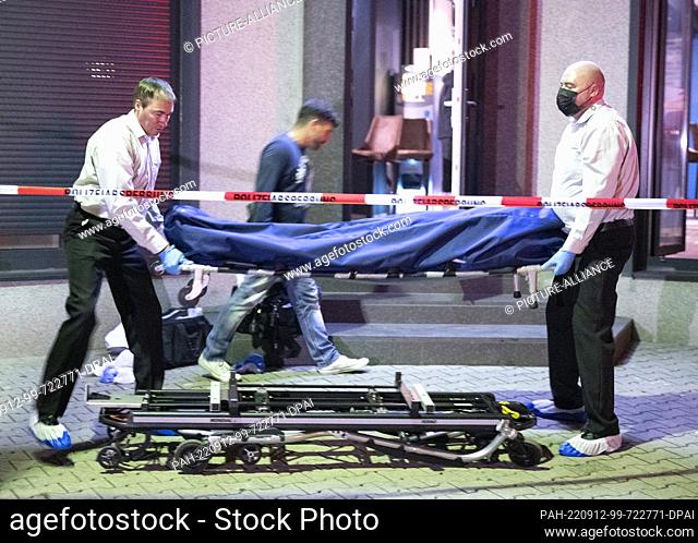 11 September 2022, Hessen, Offenbach am Main: Morticians carry the body of a victim from a bar in Offenbach. The person had been fatally injured by a gunshot