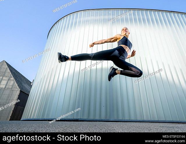 Woman practicing kickboxing by jumping in front of wall