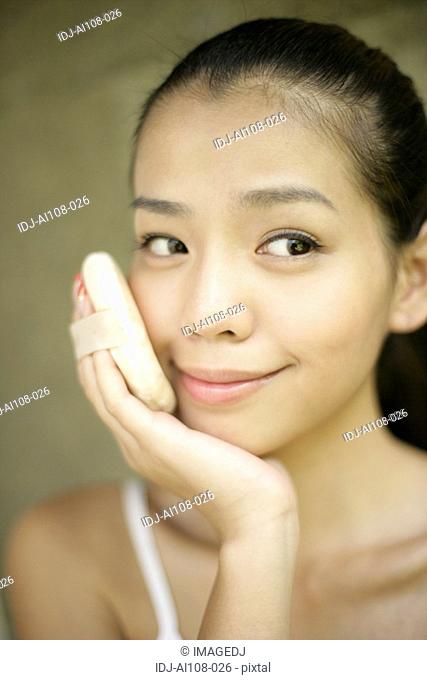 Close-up of a young woman applying powder puff