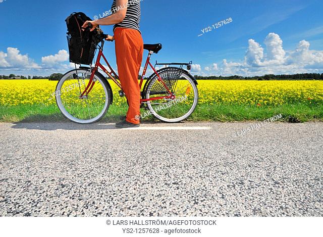 Woman with bicycle watching landscape, Östergötland, Sweden