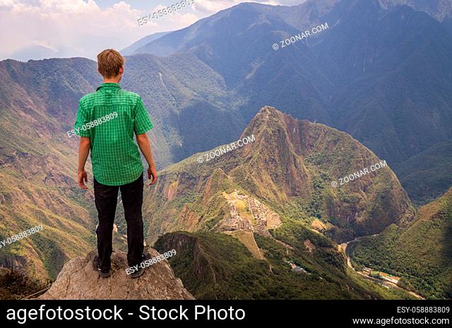 A tourist on Machu Picchu Mountain is looking down at the mysterious Inca city 600m below - Machu Picchu, PERU in October 2015