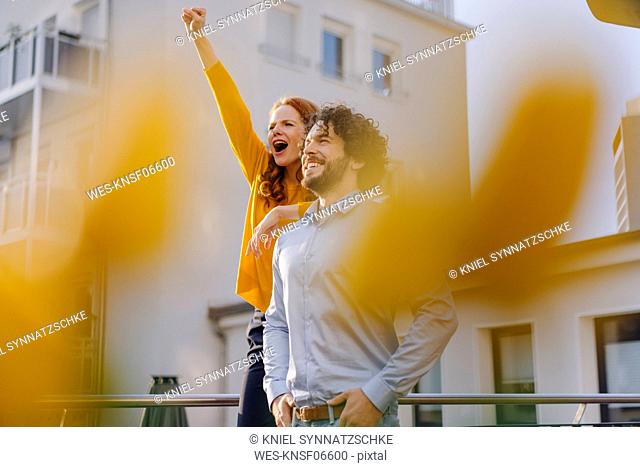 Woman with colleague on roof terrace clenching fist