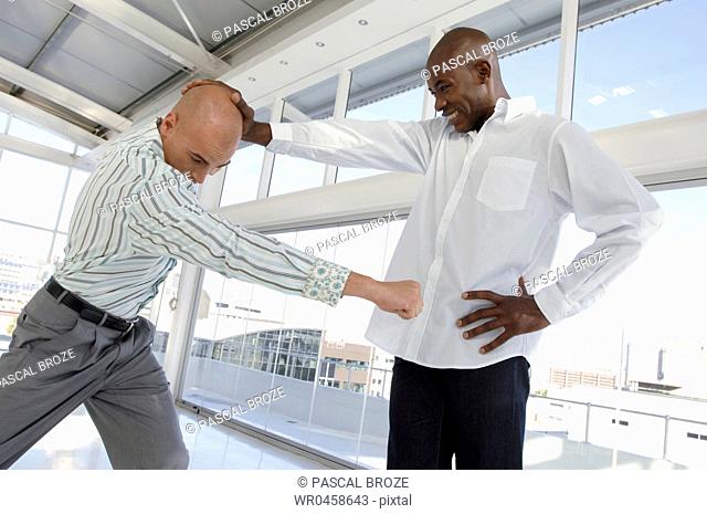 Side profile of a businessman punching another businessman