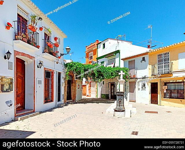 Pretty charming houses decorated with flowerpots ivy leaves in empty small square of Denia old town, spanish historical coastal city in province of Alicante...