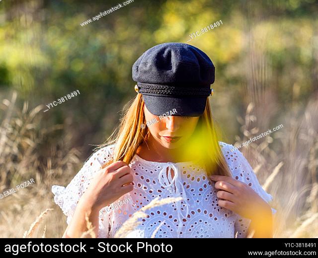 Young woman in nature in Autumn cautiously walking through grass field