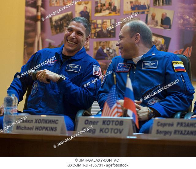 Expedition 37 NASA Flight Engineer Michael Hopkins, left, and Soyuz Commander Oleg Kotov share a laugh at a press conference held at the Cosmonaut Hotel