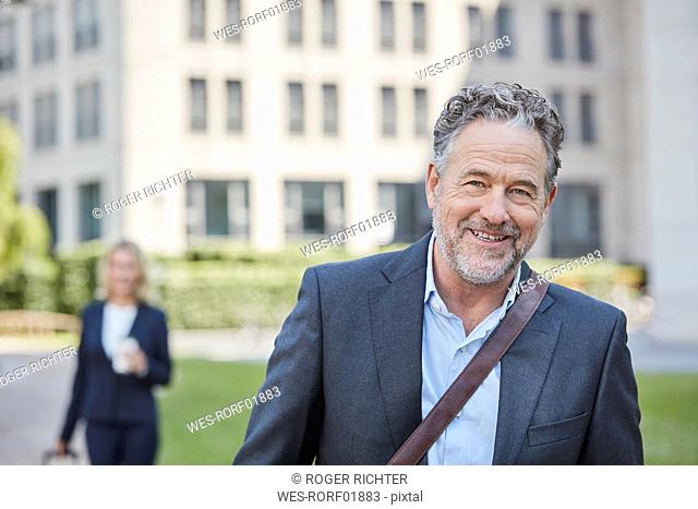 Porrait of smiling businessman in the city with businesswoman in background
